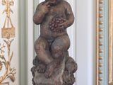 une statue représentant un bébé tenant des raisins sur une table