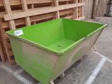 a green bin sitting on the floor in front of some pallets