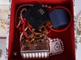 a red box filled with beads and jewelry on a table