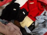a red suitcase filled with clothes and a bag of clothes