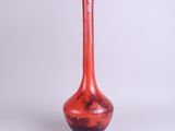 un vase rouge avec un socle noir sur fond blanc