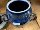 a blue vase sitting on top of a wooden table next to a plate