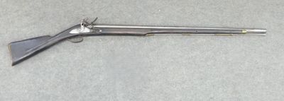 a gun that is laying on the ground next to a piece of paper
