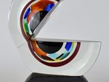 une image représentant une sculpture en verre ornée d'un motif circulaire posée sur un socle noir
