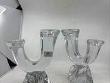 une paire de bougeoirs en verre transparent posés sur une surface blanche