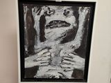 une peinture en noir et blanc représentant le visage d'une femme, posée sur un chevalet