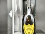 une bouteille de champagne dans un coffret, posée sur une table devant un fond noir et blanc