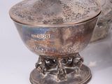 a silver bowl with spoons and spoon rest on a table