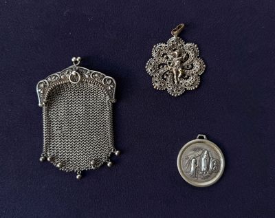 deux pendentifs en argent et une pièce en argent sur un fond bleu