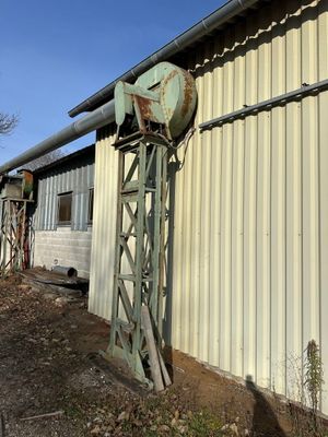 a metal structure with a clock on top of it near a building