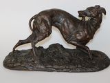 statue en bronze représentant un lévrier posé sur un rocher, sur fond blanc