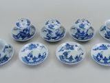 six tasses et soucoupes bleues et blanches posées sur une surface blanche