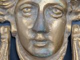a close up of a metal door handle with a face on it