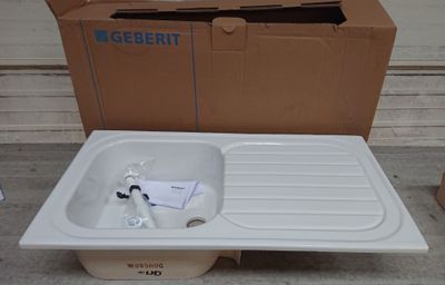 un évier blanc posé à côté d'un carton posé par terre