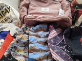 a pile of clothing and a backpack sitting on a shelf