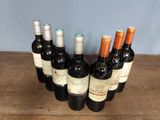 several bottles of wine are lined up in a row on a wooden table