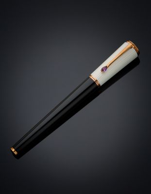 a black and white pen with gold accents on a black background