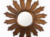 une photo d'un miroir en bois en forme de soleil accroché au mur