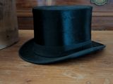 a black top hat sitting on a wooden table