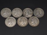 six different types of silver coins on a black surface