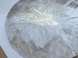 a cardboard box with a pizza in it that is wrapped in plastic