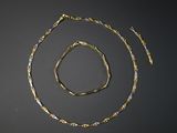 une image représentant un collier et un bracelet en or sur un fond noir