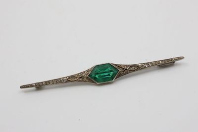 a close up of a green and white broocher on a white surface
