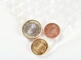 a close up of three coins in a plastic bag on a white surface