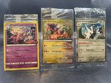 trois cartes Pokémon dans des pochettes en plastique posées sur une table