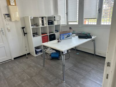 un bureau blanc sur lequel est posé un ordinateur portable, dans une pièce