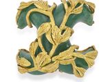 une image représentant une broche « broche » dorée et verte ornée de feuilles