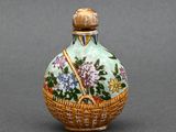 une petite bouteille en verre ornée d'un panier de fleurs
