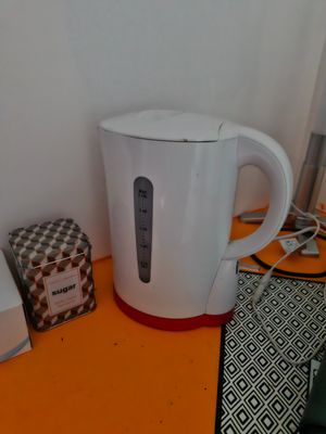 a white tea kettle sitting on a table next to a box of tea