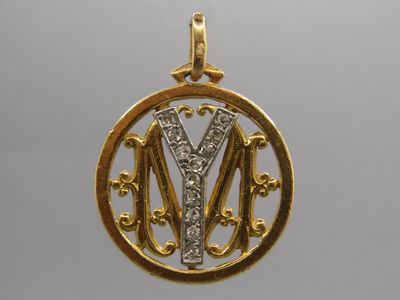 un gros plan sur un pendentif en or avec la lettre « m » au centre