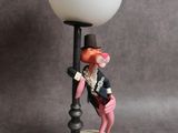 a figurine of a clown standing next to a lamp post