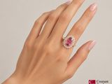 woman ' s hand with pink manicured nails holding a pink and white diamond ring