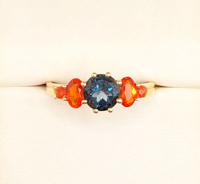 a close up of a ring with an orange and blue stone