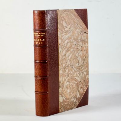 un vieux livre à la couverture marron posé sur une table blanche