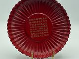 assiette en verre rouge ornée d'inscriptions en chinois, posée sur un socle doré