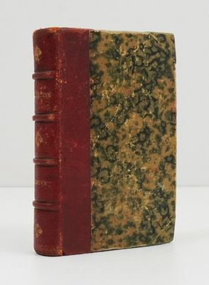 un vieux livre posé sur une table blanche à côté d'un livre rouge