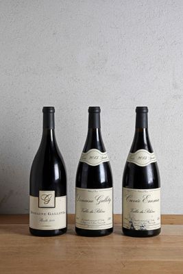 three bottles of wine are lined up on a wooden table
