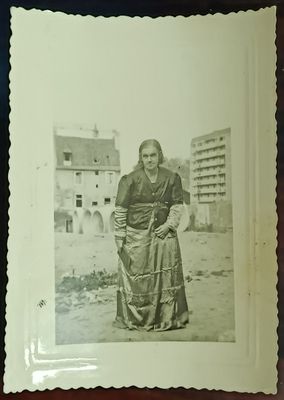 une vieille photo en noir et blanc d'une femme debout devant un immeuble