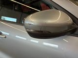 a side view mirror of a silver car in a garage