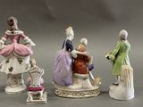 three figurines of people dressed in different colors