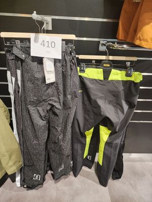 trois paires de pantalons de ski suspendues à un portant dans un magasin