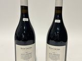 two bottles of red wine sitting next to each other on a white surface