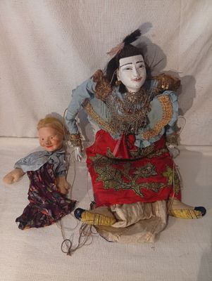 une poupée assise à côté d'une poupée assise sur une chaise
