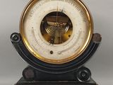 une horloge noire et dorée sur laquelle est intégré un baromètre