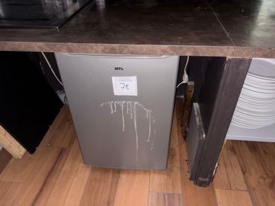 un réfrigérateur argenté posé sur un parquet dans une cuisine
