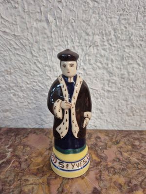 une figurine en céramique représentant un homme portant un chapeau et un manteau